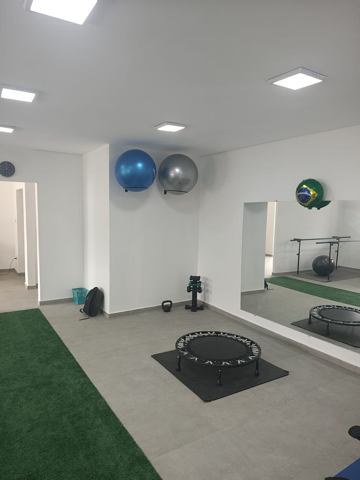 Espaço de reabilitação ativa com trampolim, bolas suíças e pista de grama sintética